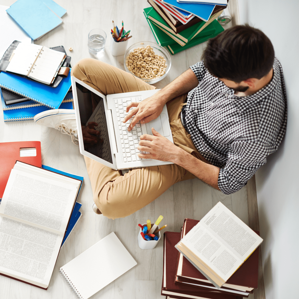 a man is studying with his laptop and his books are open